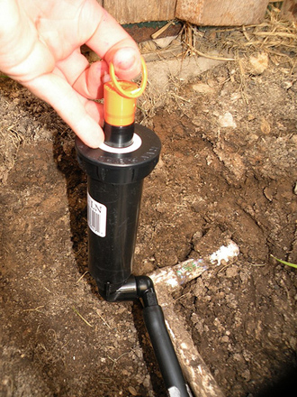 a professional Oshawa irrigation contractor is replacing a sprinkler head
